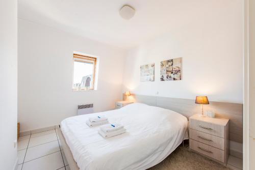1 dormitorio con 1 cama blanca y 2 mesitas de noche en Modern Apartment with Terrace & public Pool en Bredene