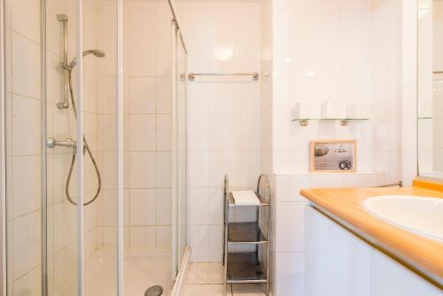 a white bathroom with a shower and a sink at Modern Apartment with Terrace & public Pool in Bredene