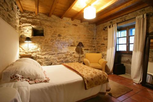 a bedroom with a bed and a stone wall at A Parada Das Bestas in Pidre
