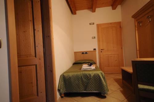 a small bedroom with a bed with a green blanket at Agritur Campo Fiorito in Dro