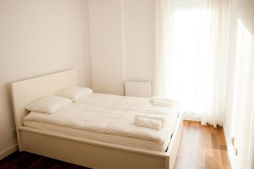 Dormitorio blanco con cama con sábanas blancas y ventana en Apartament Blu, en Łódź