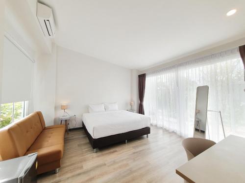 een witte slaapkamer met een bed en een bank bij MEET Boutique Resort in Suratthani