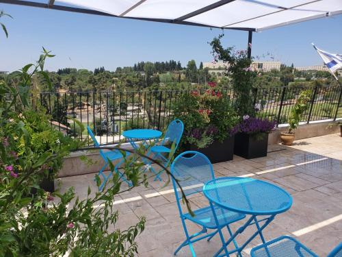 a patio with blue chairs and tables on a balcony at Biazi Hotel in Jerusalem