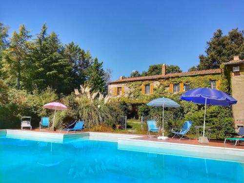 una piscina con sillas y sombrillas junto a una casa en Podere Poggio Corbo, en Chiusdino