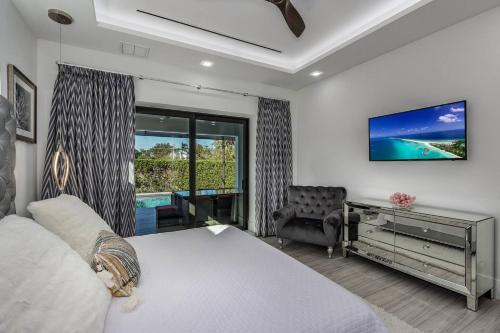a bedroom with a bed and a desk and a window at BEACH 5 MIN. WALK-LUXURIOUS MODERN POOL HOME in Marco Island
