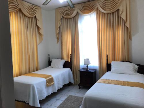 1 Schlafzimmer mit 2 Betten und einem Fenster mit Vorhängen in der Unterkunft GoldenView Guesthouse Ocho Rios in Ocho Rios