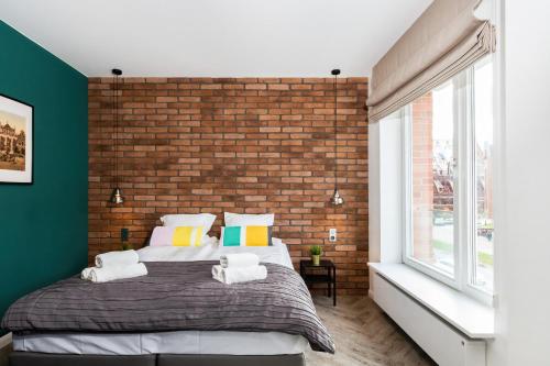 Un dormitorio con una pared de ladrillo y una cama grande en Apartments Gdańsk Rajska by Renters en Gdansk