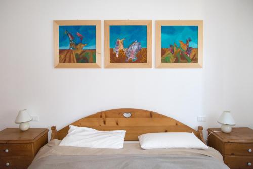 1 dormitorio con 1 cama con 3 cuadros en la pared en Green Valley Altopiano di Pinè, en Montagnaga