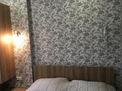 a bedroom with a bed and a wall with wallpaper at Cosy apartment near the sea in Batumi