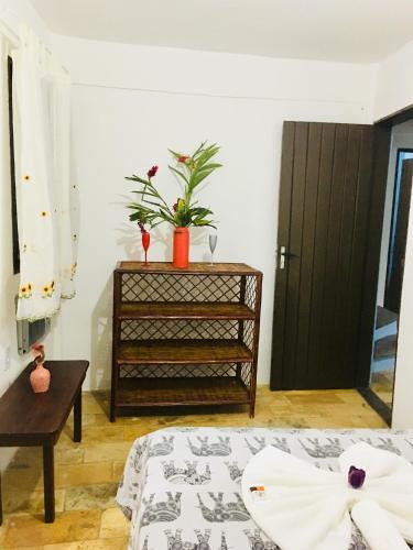 a bedroom with a bed and a plant on a dresser at Casas Coloniais in Morro de São Paulo