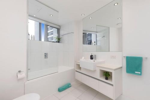 a white bathroom with a sink and a mirror at SK1 - 2 level 2 Bedroom Skyline SkyHome in Brisbane
