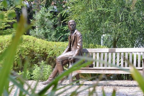 a statue of a man sitting on a park bench at Christ's College Cambridge in Cambridge