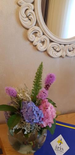 a vase of flowers sitting on a table in front of a mirror at Iris Hotel in Oradea
