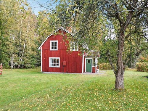 a red barn in a field with a tree at 4 person holiday home in Sk rblacka in Skärblacka