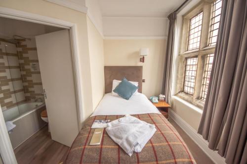 a small bedroom with a bed and a bath tub at Norfolk Arms Hotel in Arundel