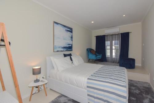 a bedroom with a white bed and a blue chair at Douro Prime Downtown in Vila Nova de Gaia