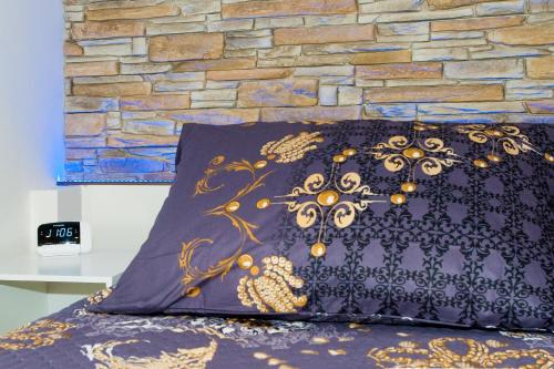 a bed with a black pillow and a stone wall at Čerti Apartmány in Liberec