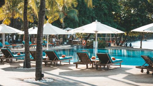 a group of chairs and umbrellas next to a swimming pool at Sands Suites Resort & Spa in Flic-en-Flac