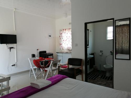 Schlafzimmer mit einem Bett, einem Tisch und Stühlen in der Unterkunft Looks cottages self catering apartments in Kasane