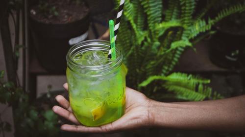 a hand holding a mason jar with a green drink at CURIOCITY Backpackers Johannesburg in Johannesburg