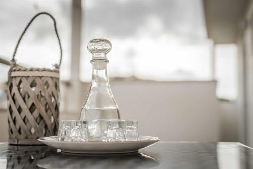 a bottle and glasses on a plate on a table at Stefanos Family Apartments in Moírai