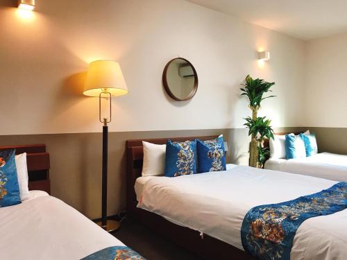 a hotel room with two beds and a lamp at Guest House One More Heart Kyoto Station South 3 in Kyoto