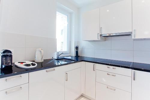 a white kitchen with white cabinets and a sink at Premium Apartments by Livingdowntown in Zürich