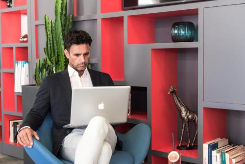 a man sitting in a chair with a laptop at iQ Hotel Milano in Milan