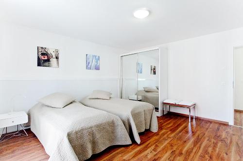 a white room with two beds and a mirror at Premium Apartments by Livingdowntown in Zürich