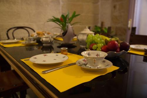 a table with two plates and a bowl of fruit at B&B Malennio in Lecce