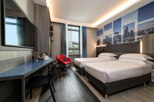 a hotel room with two beds and a desk at iQ Hotel Milano in Milan