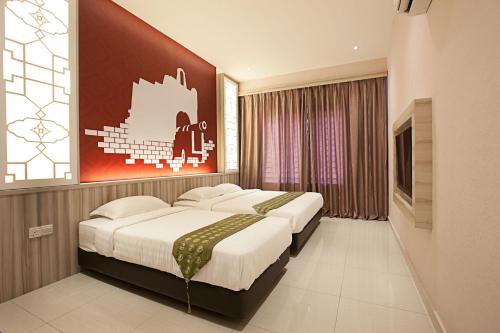 a bedroom with two beds and a painting on the wall at Sri Enstek Hotel KLIA, KLIA 2 & F1 in Sepang