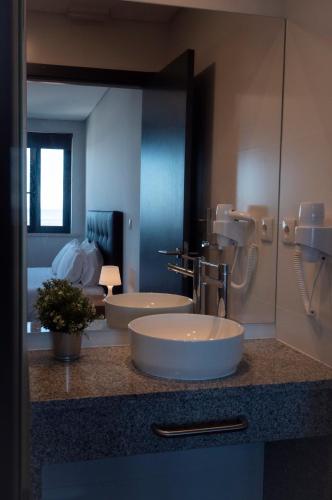 a bathroom with two sinks and a large mirror at Villa Caparica Hostel in Costa da Caparica