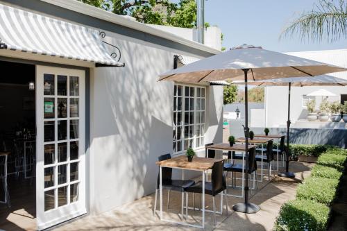 a patio with two tables and an umbrella at Elianthe Guesthouse in Swellendam