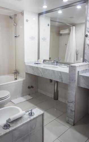 a bathroom with a sink and a toilet and a mirror at Wyndham Garden Santiago Kennedy in Santiago