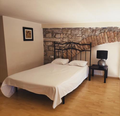 a bedroom with a bed and a stone wall at Urbi Apartments in Manresa