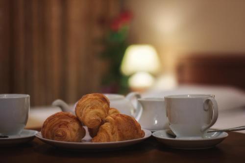 a plate of croissants on a table with two cups at Vele Rosse Hotel, business & leisure in Odesa