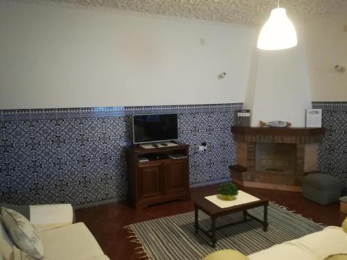 a living room with a couch and a tv and a fireplace at Casal Mala-Posta in Rio Maior