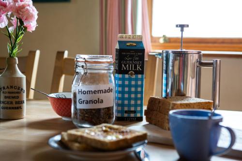 een tafel met brood, een kruik melk en een bord met eten bij The Old Forge B&B in Sark