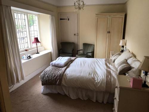 a bedroom with a bed and two chairs and a window at The Carew Arms in Taunton