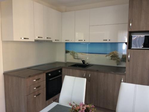 Una cocina con gabinetes blancos y una mesa y sillas. en Апартамент Мони, en Burgas