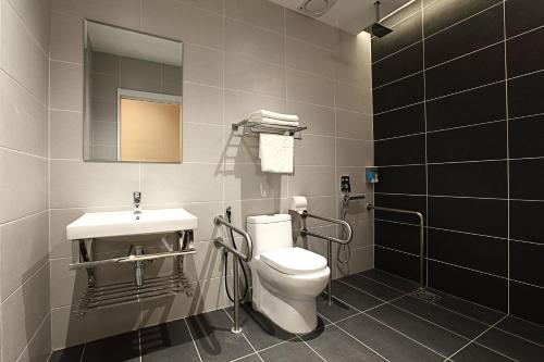 a bathroom with a toilet and a sink and a mirror at Sri Enstek Hotel KLIA, KLIA 2 & F1 in Sepang