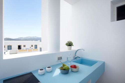 a kitchen with a blue sink and a window at Kouros Village in Antiparos Town