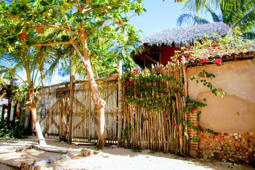 a fence in front of a house with a tree at Maria Teresa Bragança Pousada in Jericoacoara