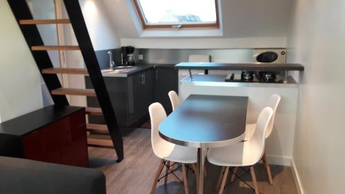 a small kitchen with a table and white chairs at Abri du pêcheur in Étel