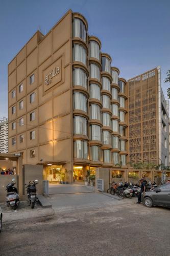 a large building with cars parked in a parking lot at Artilla Inn in Ahmedabad