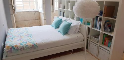 een slaapkamer met een bed met blauwe kussens en een boekenplank bij Toctoc Studio in Porto