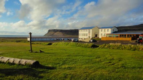 ein Gebäude inmitten eines Feldes mit dem Ozean in der Unterkunft Hotel Breidavik in Breiðavík