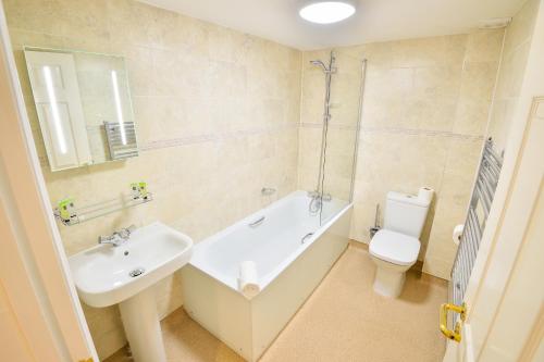 a bathroom with a sink and a tub and a toilet at The George Hotel in Axminster