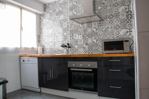 a kitchen with black cabinets and a microwave at Casaelcandano in Mieres
